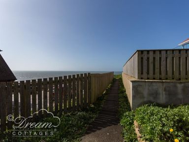 A pathway between wooden fences leading to a view of the sea at Seacliff in West Bay