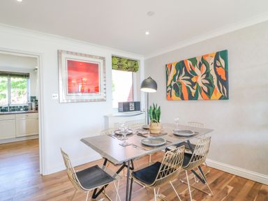 A dining room with a table set for four and abstract paintings on the wall at Sea King House in Cove Castle