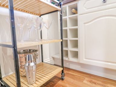 A shelf with martini glasses an ice bucket and a cocktail shaker next to a wine rack in a kitchen at Sea King House in Cove Castle