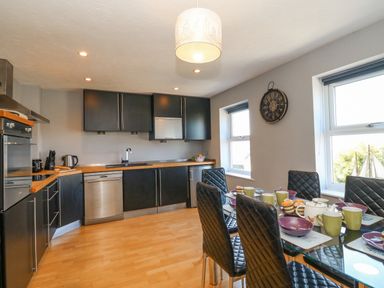 A kitchen with black cabinets wooden countertops stainless steel appliances and a dining table with black chairs at Sea Pebbles in Weymouth