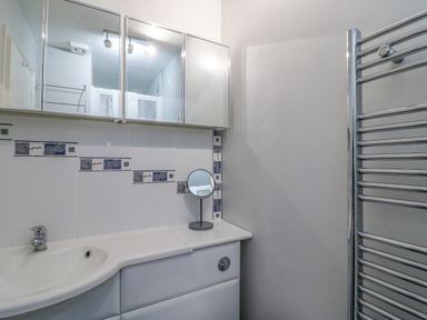 A bathroom sink with a mirror and a towel rack at Sea Pebbles in Weymouth