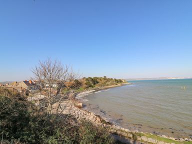 A coastal view with houses trees and a rocky shoreline at Sea Pebbles in Weymouth
