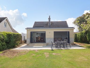 A backyard with patio furniture and open doors of a house at Shipton Hill View in Shipton Gorge