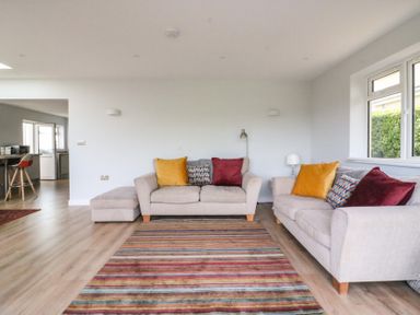 A living room with two beige sofas and a striped rug at Shipton Hill View in Shipton Gorge