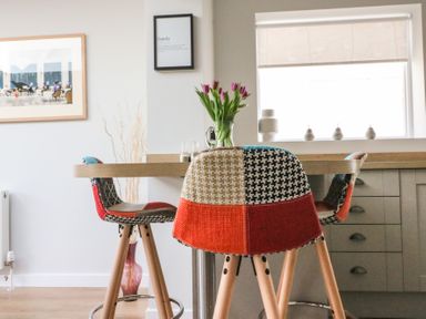 A kitchen dining area with colorful patchwork chairs a wooden table and flowers in a vase at Shipton Hill View in Shipton Gorge
