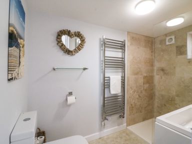 A bathroom with a toilet towel rack walk in shower and heart shaped mirror at Shipton Hill View in Shipton Gorge