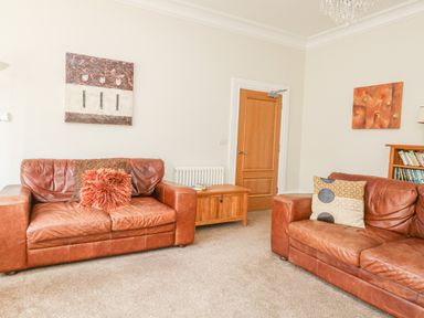 A living room with two brown leather sofas a wooden door and a wooden chest at Sea Star in Weymouth