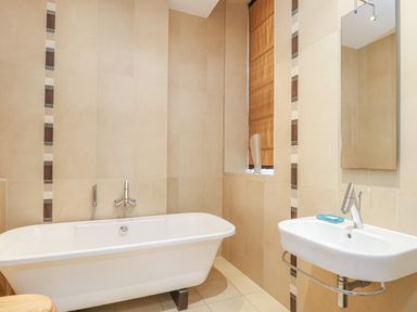A bathroom with a bathtub and a sink with a mirror above it at Sea Star in Weymouth