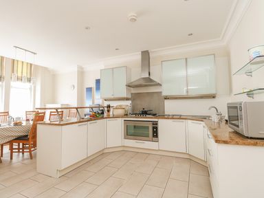 A kitchen with white cabinets a stove microwave and a dining table with chairs at Sea Star in Weymouth