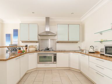 A kitchen with white cabinets brown countertops and stainless steel appliances at Sea Star in Weymouth