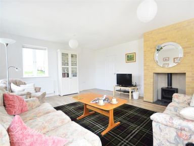A living room with a fireplace a TV on a small table sofas and a wooden coffee table at St Johns View in Portland
