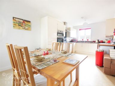 A kitchen and dining area with a wooden dining table and chairs and white kitchen cabinets at St Johns View in Portland