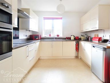 A kitchen with white cabinets, a window, red appliances, and a silver dishwasher at St Johns View in Portland