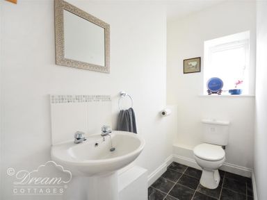 A small bathroom with a sink and mirror and a toilet near a window at St Johns View in Portland