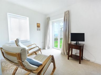 A sitting room with two armchairs a small table with a television and glass doors with curtains at St Johns View in Portland