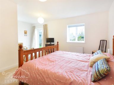 A bedroom with a wooden bed and pink bedding next to a window and a chair at St Johns View in Portland