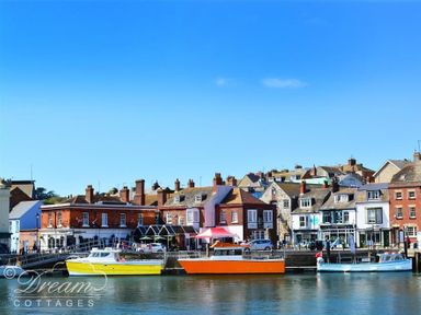 A waterfront with colorful boats docked by a row of brick and stone buildings at St Johns View in Portland