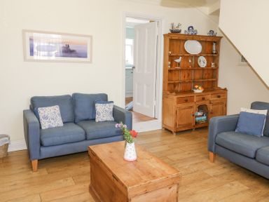 A living room with blue sofas wooden chest coffee table and wooden cabinet at Studland Cottage in Studland