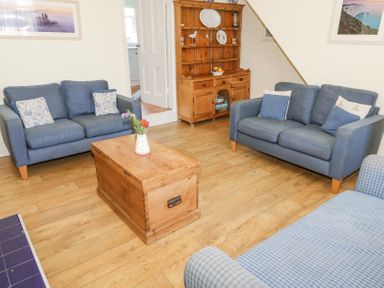 A living room with blue sofas a wooden chest as a coffee table and a wooden dresser at Studland Cottage in Studland