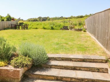 A backyard with lawn furniture and fencing at Studland Cottage in Studland
