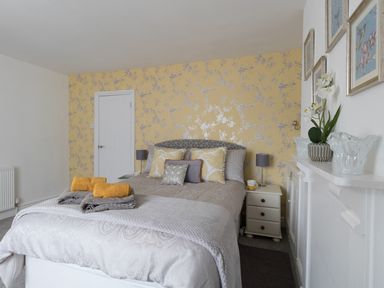 A bedroom with a bed and yellow floral wallpaper at Sunny Days in Weymouth