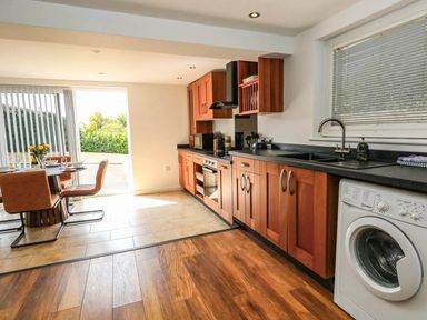 A kitchen with a dining table and washing machine at Tides Corner in Bowleaze