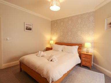 A bedroom with a double bed white bedding wooden headboard bedside tables lamps and framed pictures on walls at Tradewinds Brewers Quay Harbour