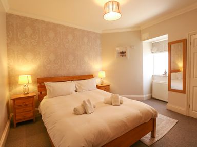 A bedroom with a double bed and bedside tables with lamps a wall mirror and a window at Tradewinds Brewers Quay Harbour