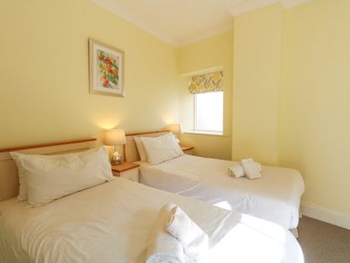 A bedroom with two single beds bedside tables with lamps and a window at Tradewinds Brewers Quay Harbour