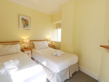 A bedroom with two single beds side by side with lamps on bedside tables and a small window at Tradewinds Brewers Quay Harbour