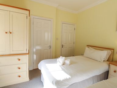 A bedroom with a single bed white wardrobe and two closed doors at Tradewinds Brewers Quay Harbour