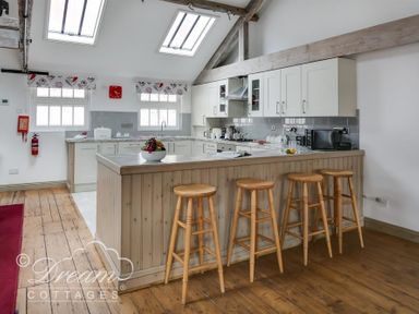 A kitchen with wooden stools at a counter and white cabinets at Upsidedown House in Brewers Quay Harbour