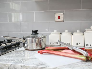 A kitchen counter with a stove saucepan jars labeled coffee sugar tea biscuits and rhubarb with a knife at Upsidedown House Brewers Quay Harbour