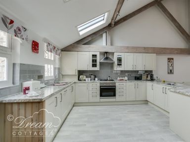 A kitchen with white cabinets and gray countertops under a skylight at Upsidedown House in Brewers Quay Harbour