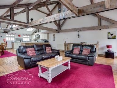A living room with two black leather sofas a wooden coffee table and kitchen in the background at Upsidedown House Brewers Quay Harbour