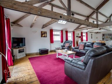 A living room with leather sofas a wooden coffee table red curtains and exposed wooden ceiling beams at Upsidedown House Brewers Quay Harbour