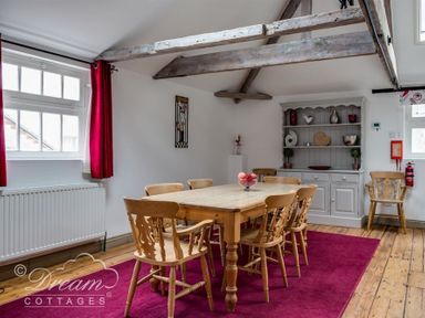 A dining room with wooden table and chairs a cabinet and exposed ceiling beams at Upsidedown House in Brewers Quay Harbour