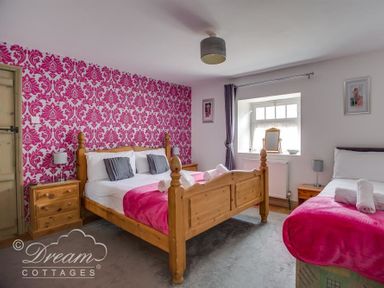 A bedroom with a double bed and a single bed both with pink blankets and wooden furniture at Upsidedown House Brewers Quay Harbour