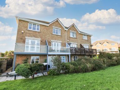 A brick residential building with balconies and a grassy lawn at Waters Edge in Wyke Regis