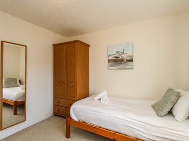 A bedroom with a single bed wooden wardrobe wall mirror and painting at Waters Edge in Wyke Regis