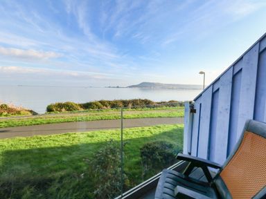A balcony with two chairs overlooking a grassy area a path and a body of water at Waters Edge in Wyke Regis