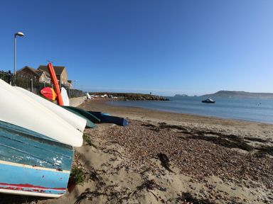 Boats on sandy beach near houses and calm sea with a distant skyline at Waters Edge in Wyke Regis