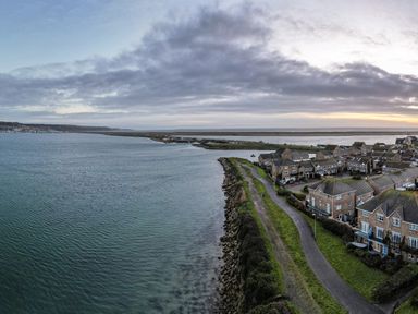 A coastal residential area with houses along a waterfront path at Waters Edge in Wyke Regis