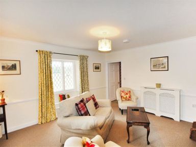 A living room with sofas a coffee table and yellow curtains at Warmwell Lodge in Warmwell