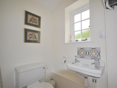 A bathroom with a toilet, a sink, a window, and two framed pictures on the wall at Warmwell Lodge in Warmwell