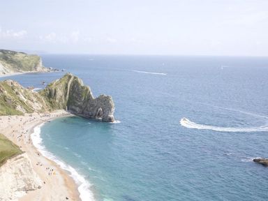 A coastal scene with a sandy beach cliffs and a boat moving on the sea at Warmwell Lodge in Warmwell
