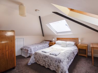 A bedroom with two beds a wooden wardrobe bedside tables and a skylight window at Waterson in Osmington