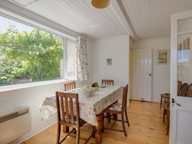 A dining room with a wooden table and chairs near a large window at Waterson in Osmington