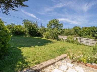 A backyard with grass lawn surrounded by trees and a wooden fence at Waterson in Osmington