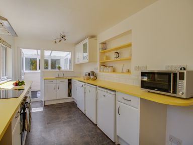 A kitchen with yellow countertops white cabinets a microwave and a window at Waterson in Osmington